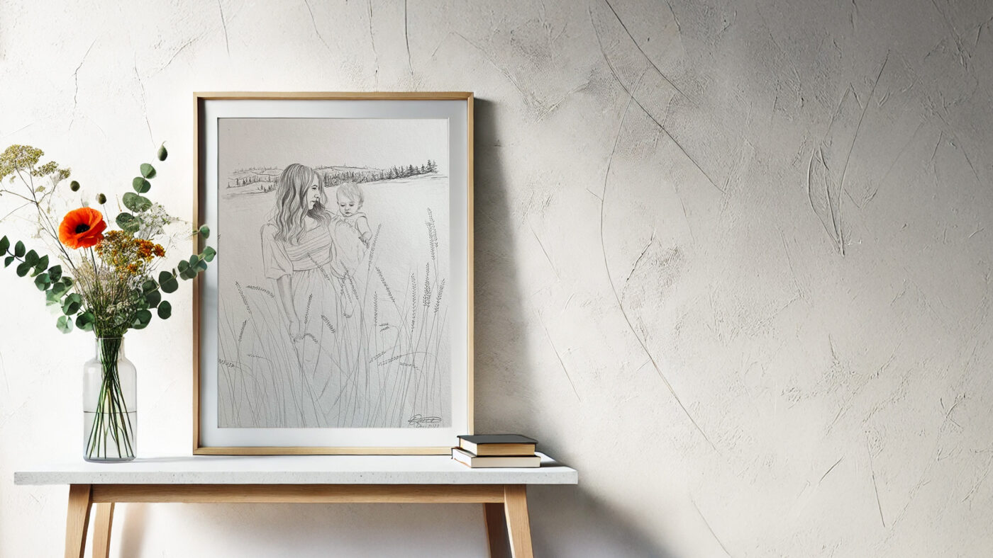A custom pencil drawing of a mother and child in a field, framed and displayed on a minimalist wooden table with a floral vase and books.